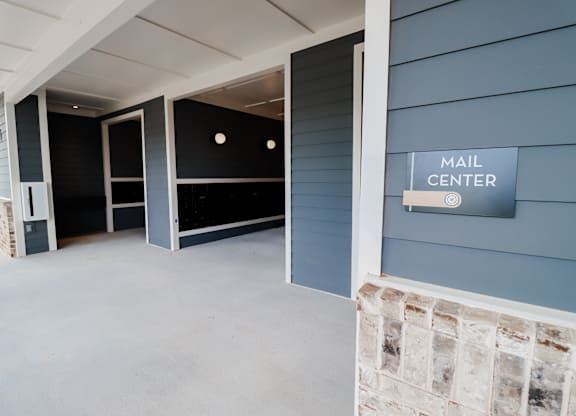 Covered parking garage with mail center and stone accent wall at The Crest at South Point Apartments, McDonough, GA 30253