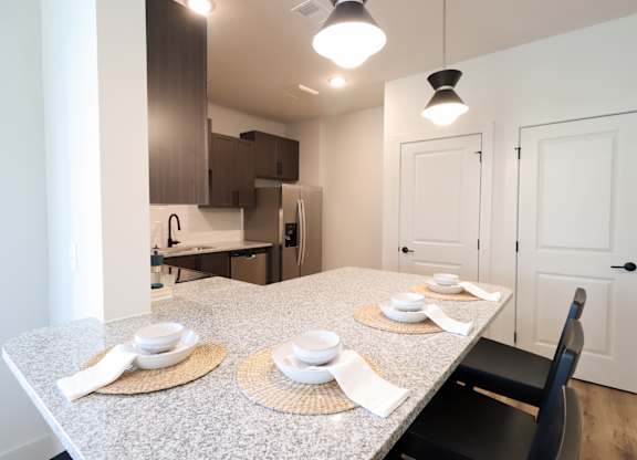 Dining area with granite peninsula and place settings at The Crest at South Point Apartments, McDonough, 30253