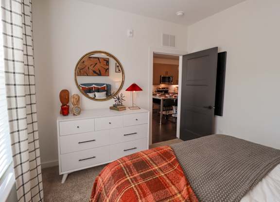 Bedroom with white dresser and round mirror at The Wren Apartments, Georgia