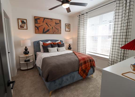 Bedroom with upholstered bed and modern decor at The Wren Apartments, Lawrenceville, GA