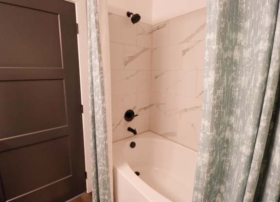 Bathroom with soaking tub and marble tile surround at The Wren Apartments, Georgia, 30043
