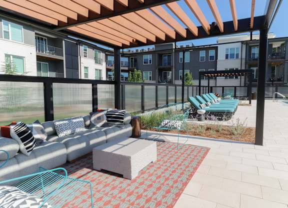 Outdoor lounge area with pergola and poolside seating at The Wren Apartments, Lawrenceville