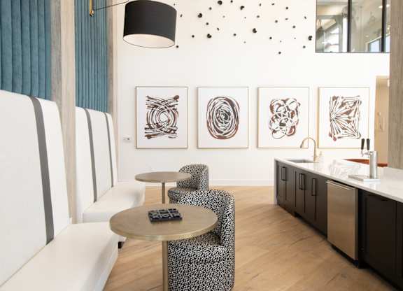 Lounge seating with abstract wall art and kitchenette at The Wren Apartments, Lawrenceville, Georgia