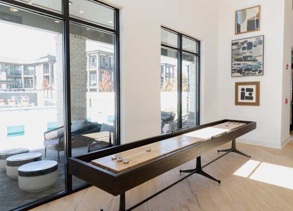 Shuffleboard table in community game room with wall art at The Wren Apartments, Lawrenceville, GA 30043