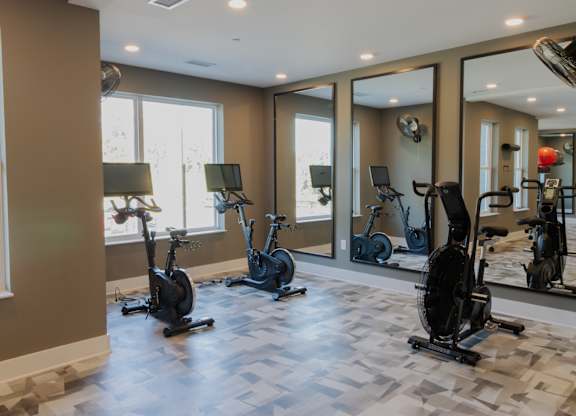 Fitness center with stationary bikes and wall mirrors at The Wren Apartments, Georgia