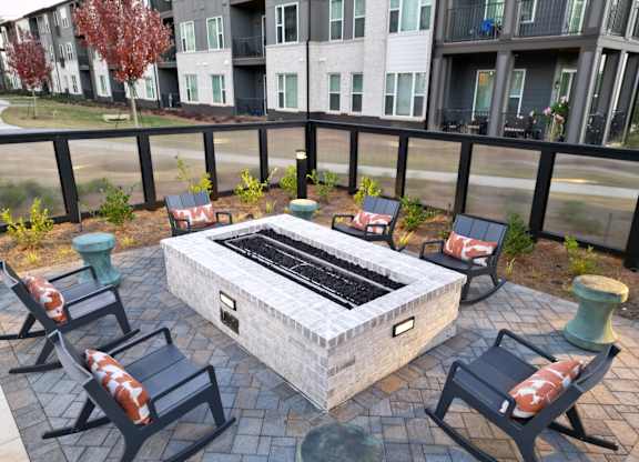 Outdoor fire pit seating area with lounge chairs at The Wren Apartments, Lawrenceville, GA 30043