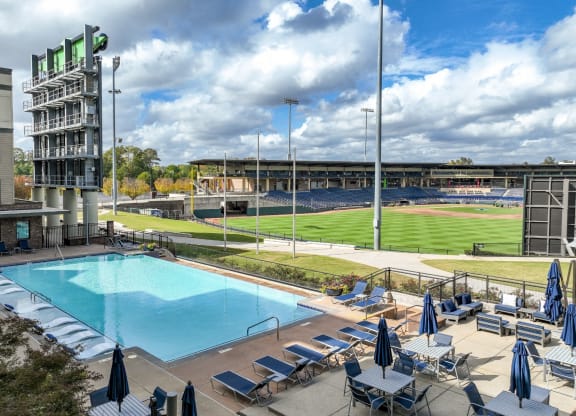 an aerial view of a swimming pool with a baseball field in the background