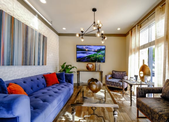 a living room with blue couches and chairs and a glass table
