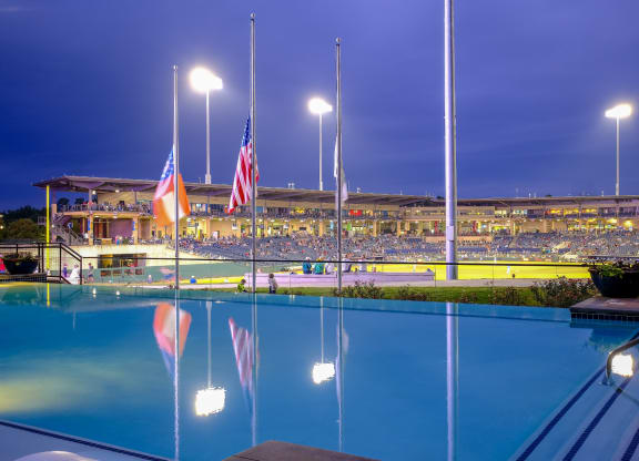 a view of a swimming pool, flags and a stadium in the background