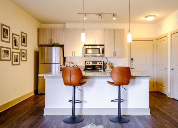 a photo of a kitchen island with bar stools and kitchen in the background