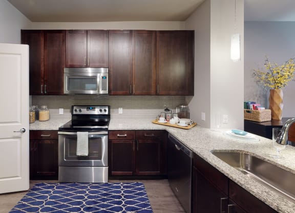 a kitchen with dark wood cabinets and a blue rug