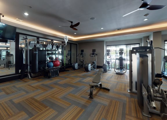 a spacious fitness room with cardio equipment and a flat screen tv