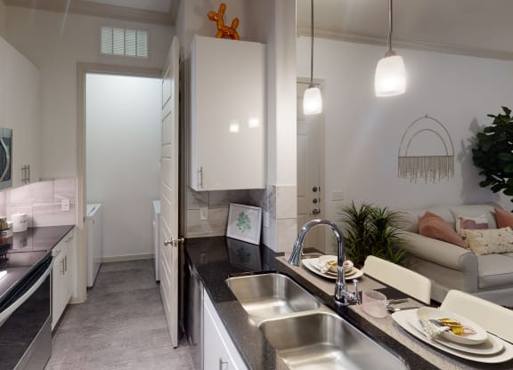 a kitchen with white cabinets and black countertops
