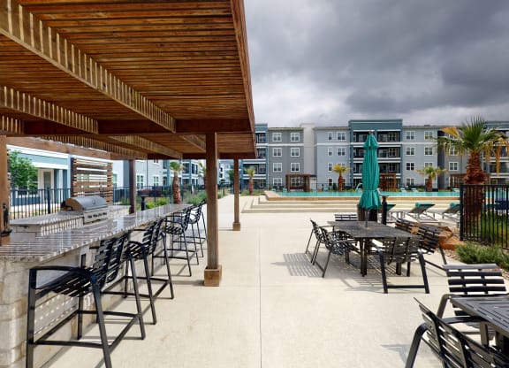 a patio with tables and chairs and a pool in the background