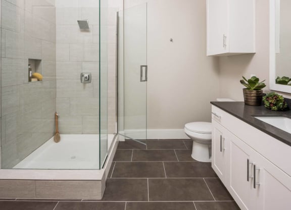 spacious bathroom with glass framed shower doors at Tinsley on the Park apartments