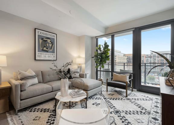 an open living room with a couch and large windows in Tribeca NOMA apartments