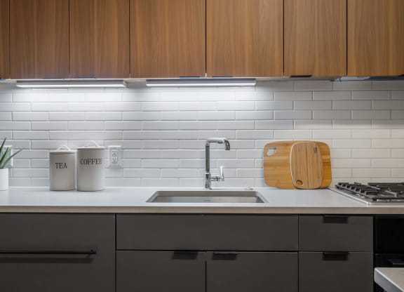 A white kitchen counter with a sink and wooden cabinets at Tribeca NOMA apartments