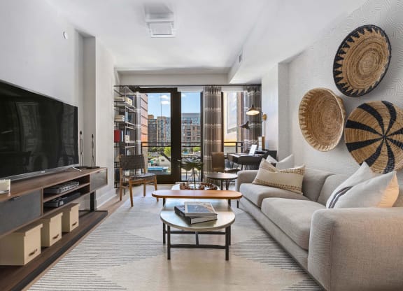 a living room with a couch and a tv and a balcony at Tribeca NOMA apartments