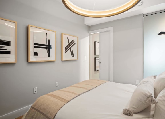 a bedroom with a bed and modern light fixture at Tribeca NOMA apartments