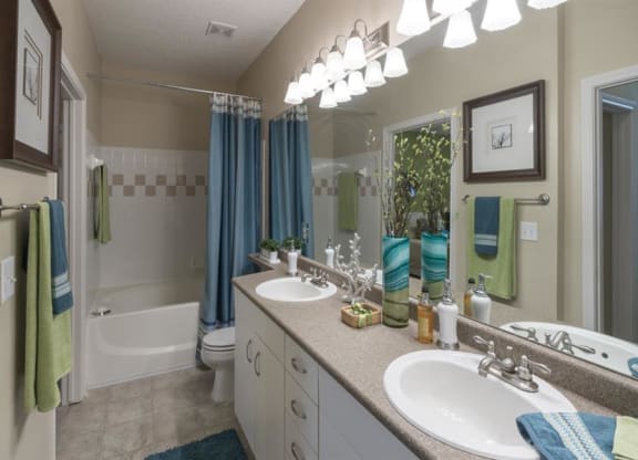 Master bathroom with floating vanities, quartz countertops, backlit vanity mirror, walk-in shower with Euro shower door and quartz-topped bench seat at Wyndchase  Aspen Grove, Tennessee, 37067
