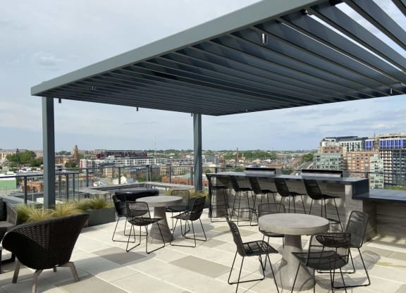 a rooftop patio with tables and chairs and a view of the city at Tribeca NOMA apartments
