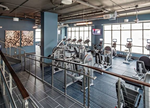 a gym with cardio machines and large windows at Reveal Hackensack apartments