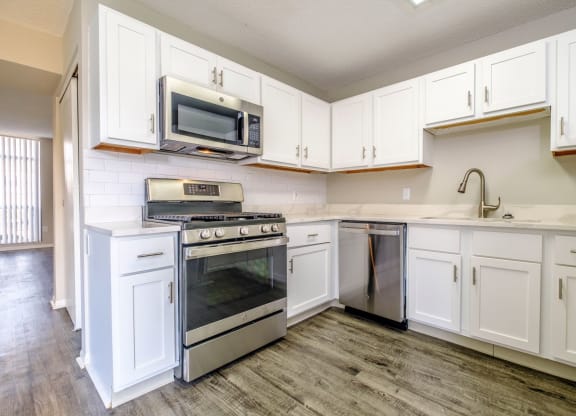 a kitchen with white cabinets and stainless steel appliances