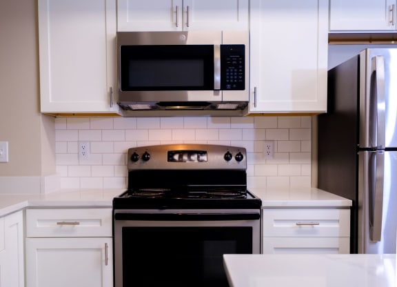 a kitchen with white cabinets and stainless appliances