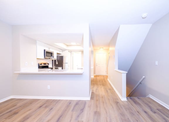 a spacious living area with hardwood floors and a kitchen in the background