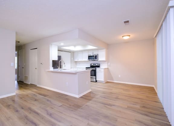 a spacious living room with a kitchen in the background