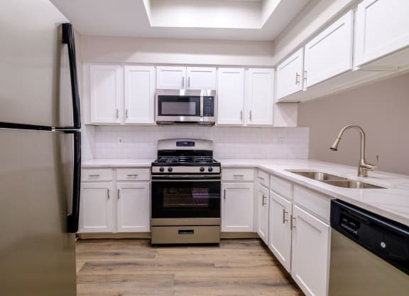 a kitchen with white cabinets and stainless steel appliances