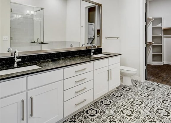a bathroom with white cabinets and designer lighting at The Gabriella apartments