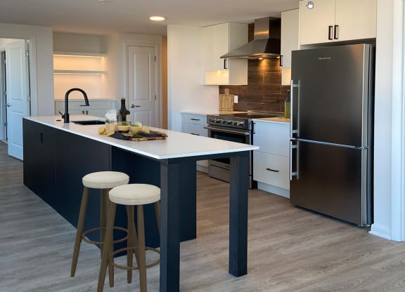 a kitchen with a center island with two stools at The Millennium, Arlington, VA, 22202