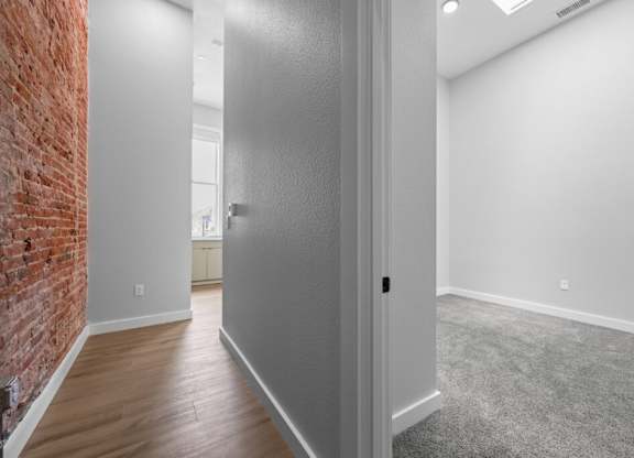 A room with a grey door and a brick wall on the left side at The Avenue Lofts Golden Apartments, Colorado