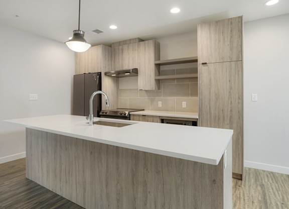 A modern kitchen with a white countertop and wooden cabinets at The Avenue Lofts Golden Apartments, Colorado