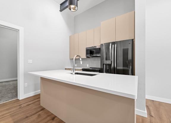 A kitchen with a white counter and beige cabinets at The Avenue Lofts Golden Apartments, Golden, CO, 80401
