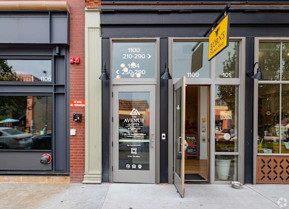 The front of a building with a grey facade and a glass door.