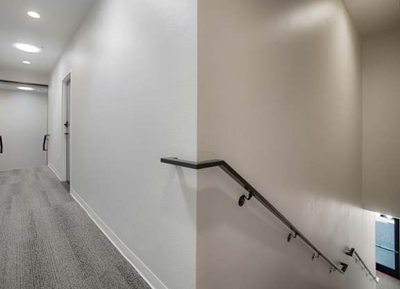 A hallway with a staircase and a carpeted floor at The Avenue Lofts Golden Apartments, Golden 80401