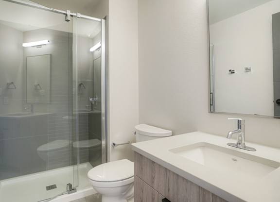 A white toilet sits next to a sink in a bathroom at The Avenue Lofts Golden Apartments, Golden, Colorado