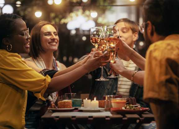 A group of people toasting with glasses of wine at a dinner table.