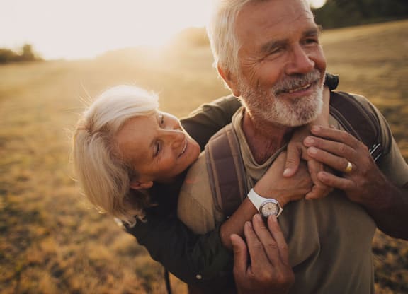 an older couple embraces in a field as the sun sets at Brownstones at Palisade Park,  Colorado