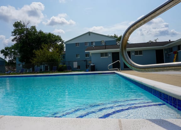 Swimming Pool Entry with pool chairs and apartment building, at Gale Gardens