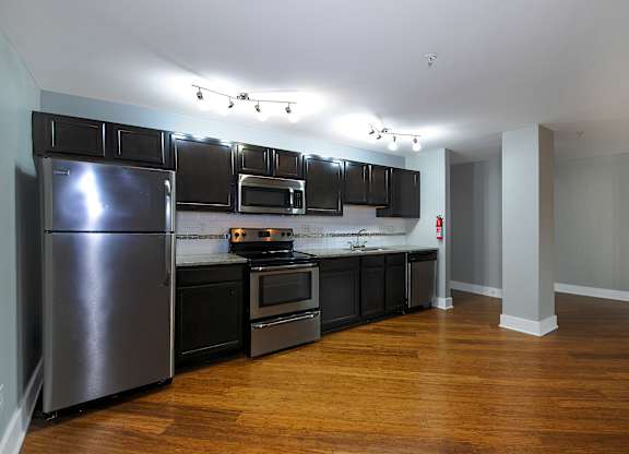 A kitchen with a refrigerator, oven, and microwave.