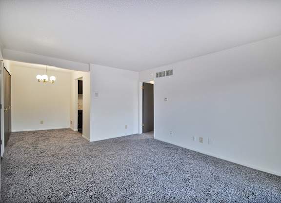 A large empty room with carpeted floor and white walls.