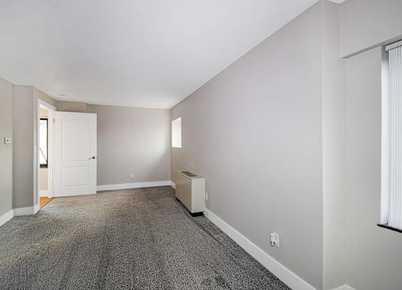 A room with a carpeted floor and a white door.