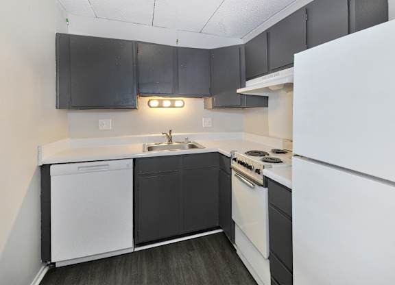 A kitchen with black cabinets and white appliances.