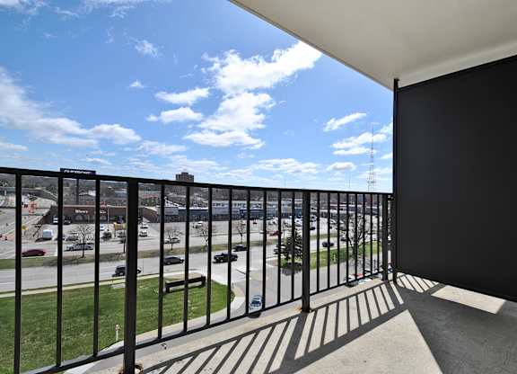 A balcony with a black railing overlooks a parking lot.