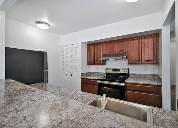 A kitchen with granite countertops and wooden cabinets.