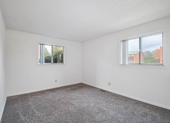 A room with two windows and carpeted floor.