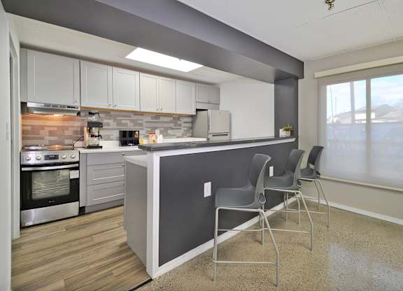 A kitchen with a grey island and white cabinets.